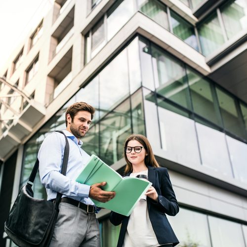 a-young-businessman-and-businesswoman-standing-in-LM5QHAS